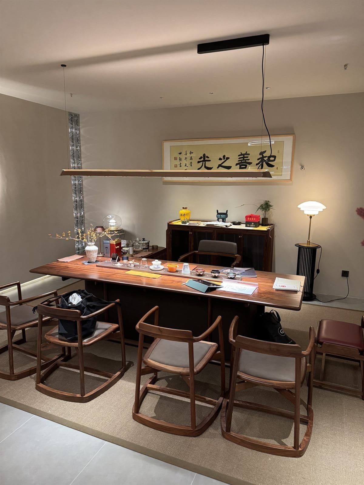A long linear wooden GUOCIO pendant light illuminating a large wooden desk in a room with traditional Chinese decor