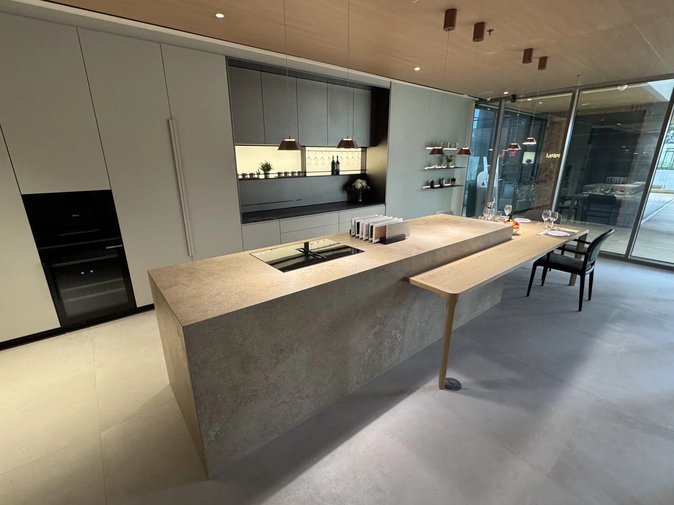 The Asoke showroom kitchen, with a stone waterfall island and an integrated oak dining table