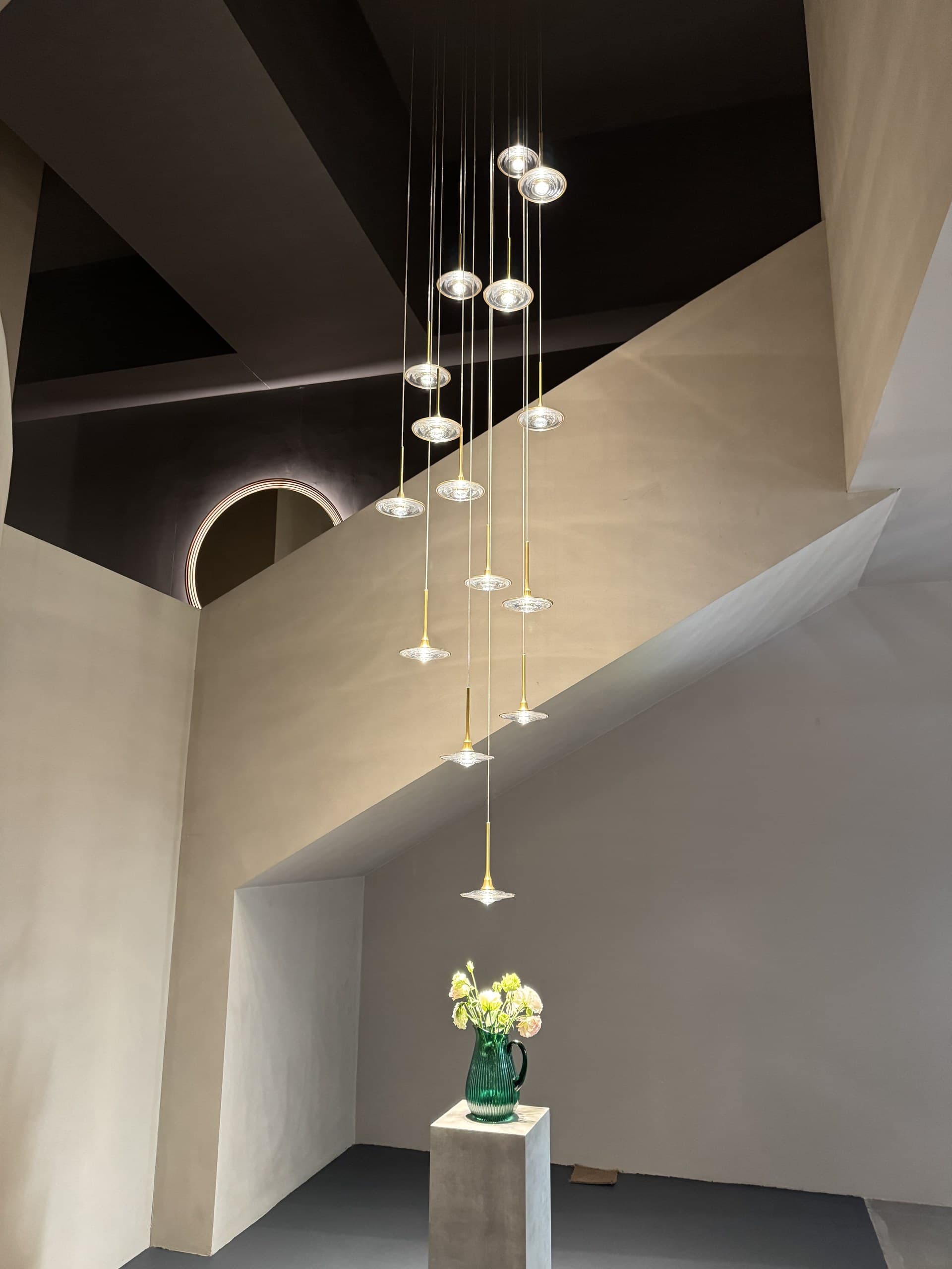 A multi-light pendant fixture with clear glass shades hangs in a modern interior space with geometric wall designs.